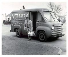 an old black and white photo of a man standing in front of a food truck