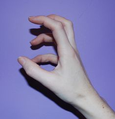 a person's hand reaching for something on a purple background with their fingers extended