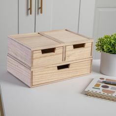 a wooden box sitting on top of a white table next to a potted plant