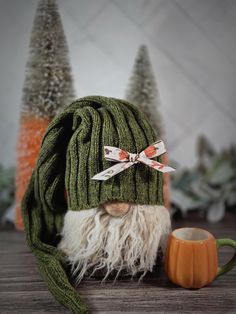 a green knitted hat with white fur and an orange mug on a wooden table