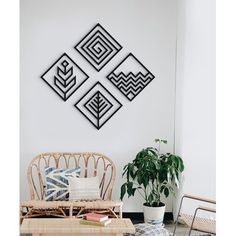 three black metal wall art pieces hanging on a white wall above a wicker coffee table