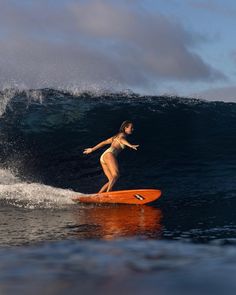 a woman riding a surfboard on top of a wave