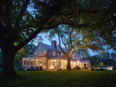 a large house sitting on top of a lush green field next to a tall tree