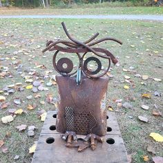 an owl sculpture sitting on top of a piece of wood