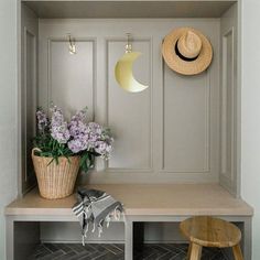 a bench with some flowers and a hat on top of it next to a wall