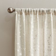 a curtain with white flowers on it hanging from the side of a window sill