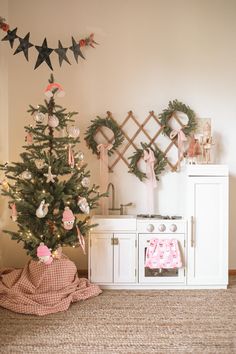 a small christmas tree sitting in the corner of a room next to a stove top oven