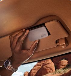 a woman's hand is holding an electronic device in the back seat of a car