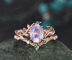 a pink ring with leaves on it sitting on top of a green rock in front of a