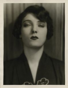 an old black and white photo of a woman with her eyes closed in front of the camera