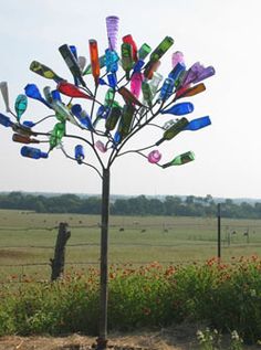 a tree made out of plastic bottles in the middle of a field