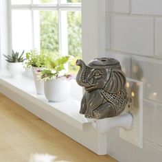 an elephant figurine sitting on top of a window sill