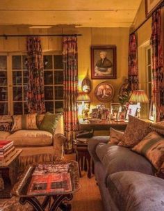 a living room filled with lots of furniture and windows covered in drapes, pillows and curtains