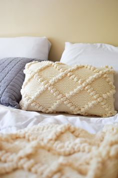 a white bed topped with pillows and blankets