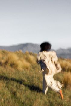 a person running in the grass with a frisbee