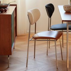 three chairs sitting on top of a hard wood floor next to a table with a bowl of fruit