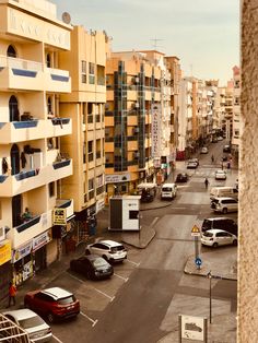 cars are parked on the side of an empty street in front of apartment buildings and parking spaces