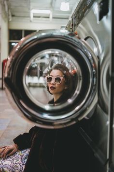 a woman sitting in front of a washing machine