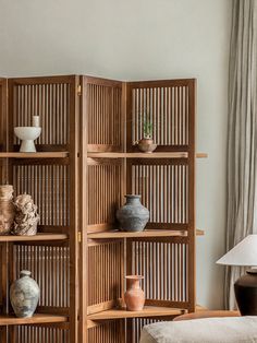 a room divider made out of wood with vases on the top and bottom shelves