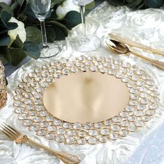 the table is set with gold and crystal plates, silverware, and napkins