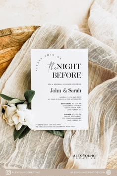 a wedding card with flowers on top of it next to a cloth covered tablecloth