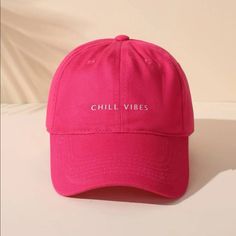 a pink chill vibes hat sitting on top of a white table next to a wall