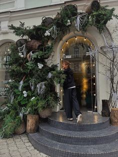 a woman standing in front of a building with christmas decorations on the outside and inside