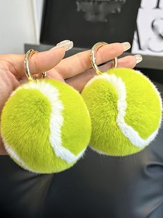 two green and white tennis balls are being held by someone's hand