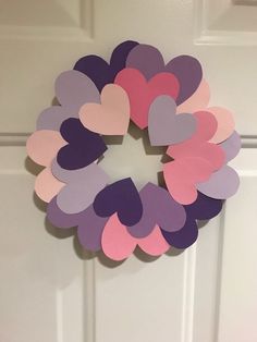 a wreath made out of paper hearts hanging on the front door to celebrate valentine's day