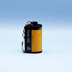 an empty battery keychain sitting on top of a white surface with a blue sky in the background