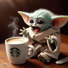 an adorable baby yoda doll sitting next to a cup of coffee with steam coming out of it