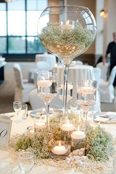 the centerpiece is filled with candles and greenery, surrounded by glass vases