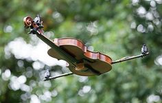 an old violin hanging upside down in the air with trees in the back ground behind it