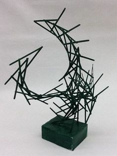 a sculpture made out of sticks on top of a green box with a white background