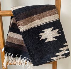 a black and brown blanket sitting on top of a wooden chair