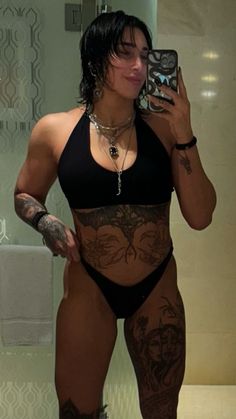 a woman with tattoos taking a selfie in the bathroom