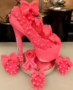 a pair of pink high heeled shoes with bows and pearls on the side, sitting on top of a counter