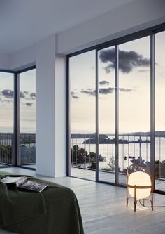 a bedroom with large windows overlooking the water