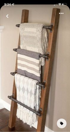 a wooden ladder holding towels and blankets on top of a hard wood floor next to a fireplace