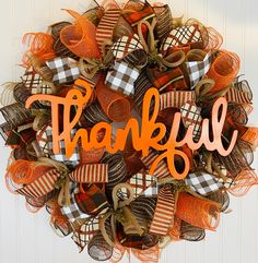 a wreath with the word happy written in orange, black and white letters on it