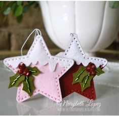 two felt christmas decorations hanging from strings on a table