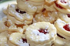 a plate filled with cookies covered in powdered sugar and cranberry jelly toppings