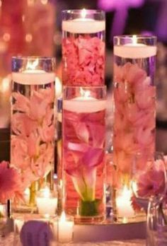 pink flowers and candles are arranged in glass vases