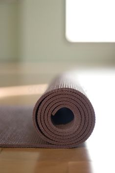 a rolled up yoga mat sitting on top of a wooden floor