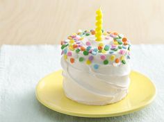 a birthday cupcake with white frosting and sprinkles on a yellow plate