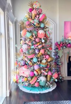 a brightly colored christmas tree in the corner of a room with pink and blue decorations