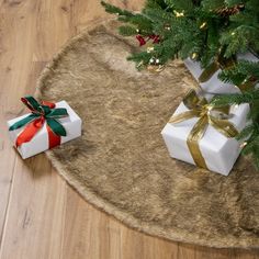 two wrapped presents sitting on top of a rug next to a christmas tree