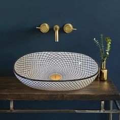 a bathroom sink sitting on top of a wooden counter next to a vase with flowers