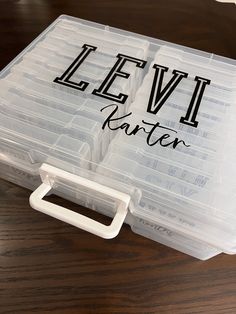 a plastic storage box with the words levi written on it and an open lid sitting on top of a wooden table