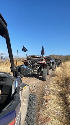 four atvs parked on the side of a dirt road in front of an off - road vehicle